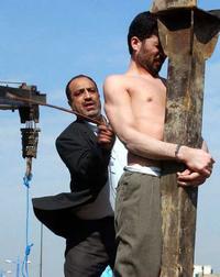 A judicial officer whips Mohammad  Bijeh just before the murderer was hanged using a crane.